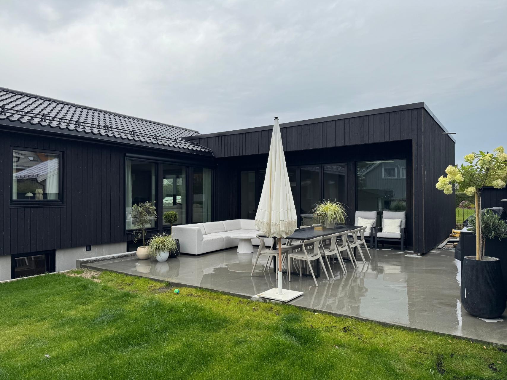 Svart moderne bolig med møblert uteplass og terrasse