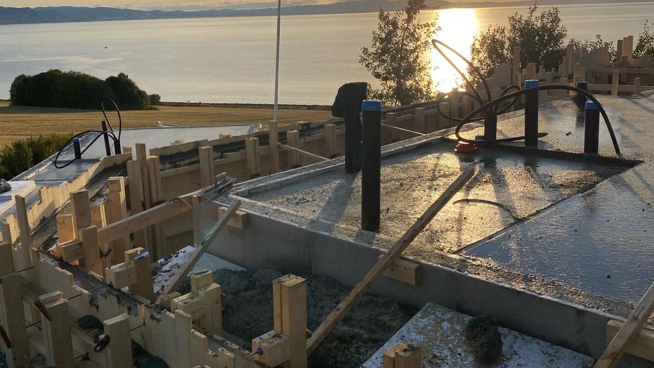 Grunnmur under bygging med utsikt mot fjorden i solnedgang
