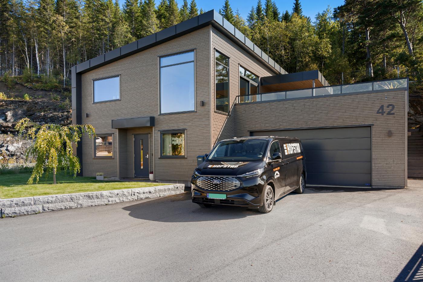 Moderne enebolig med stor garasje og Hofstad-varebil foran