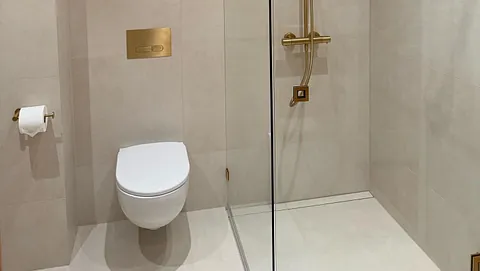Moderne bad med vegghengt toalett og dusj med detaljer i messing