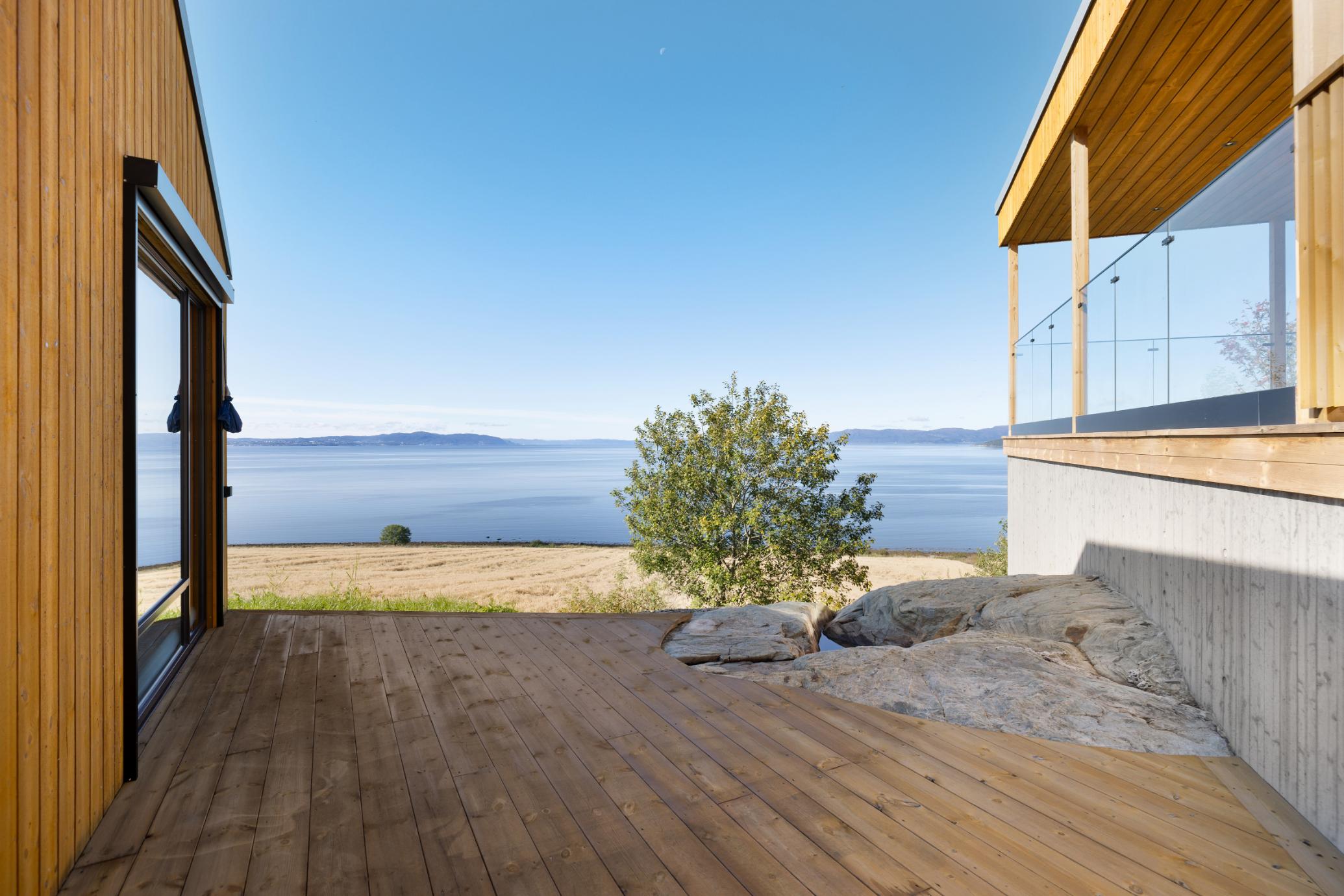Terrasse mellom trehus med utsikt over fjorden